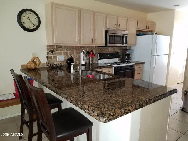 a kitchen with stainless steel appliances granite countertop a sink a stove a microwave a refrigerator and a stove