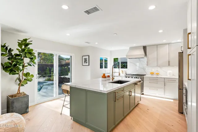 a kitchen with stainless steel appliances a table chairs in it and wooden floors