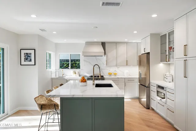 a living room with stainless steel appliances kitchen island granite countertop furniture and a wooden floor