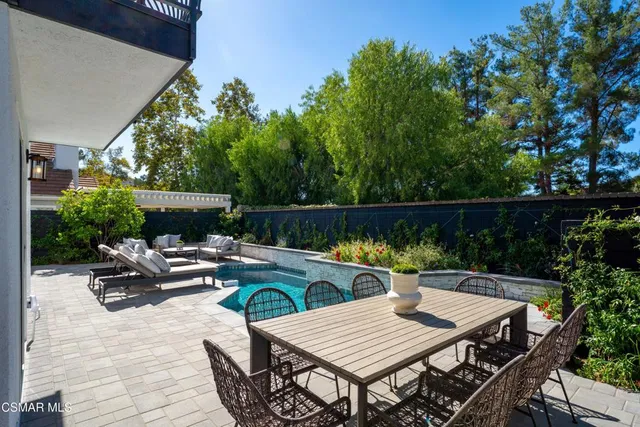 a view of swimming pool with seating space and trees in the background
