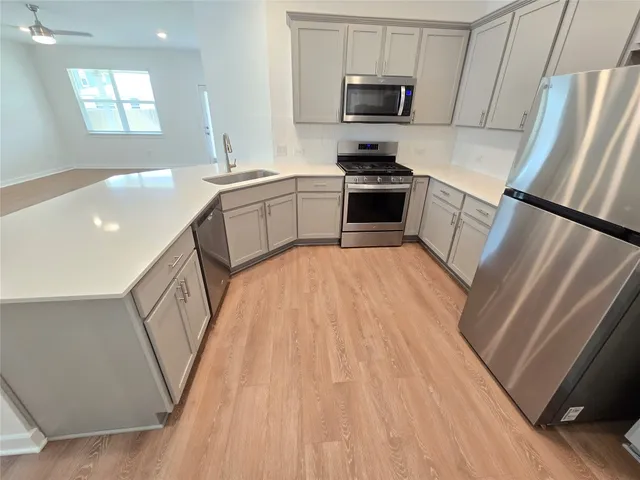 a view of a kitchen with wooden floor electronic appliances and windows