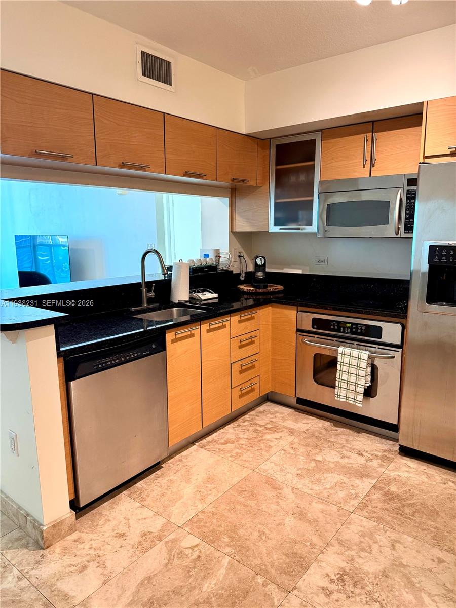 31 Southeast 5th Street, Unit 2710 Miami, FL 33131 - Photo 4 of 25 a kitchen with stainless steel appliances granite countertop a stove a sink and a microwave