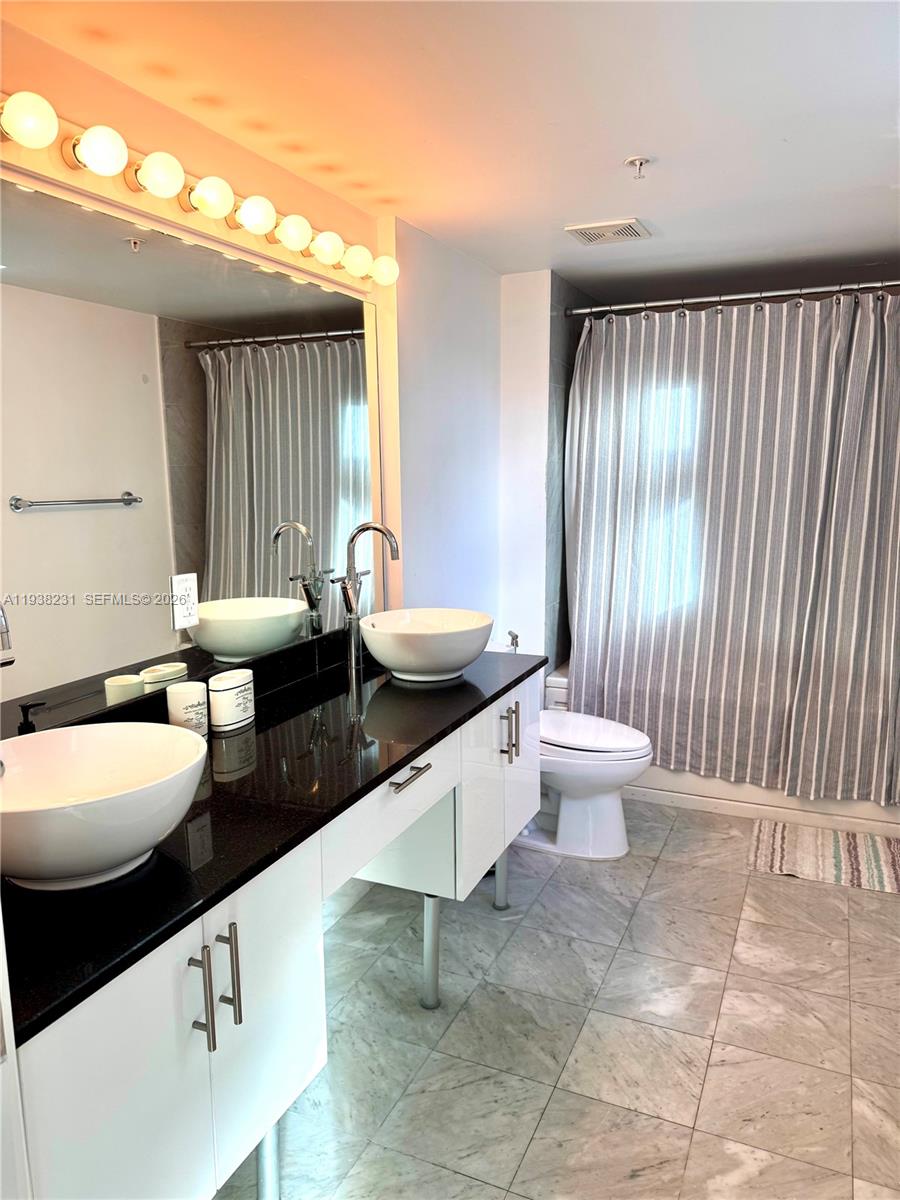 31 Southeast 5th Street, Unit 2710 Miami, FL 33131 - Photo 9 of 25 a bathroom with a double vanity sink toilet and a tub
