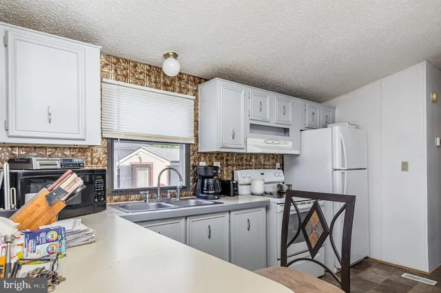 a kitchen with stainless steel appliances granite countertop a sink refrigerator and cabinets