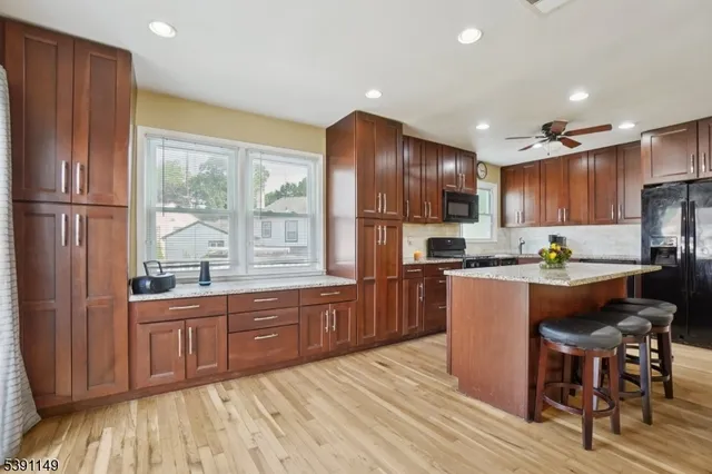 a kitchen with stainless steel appliances granite countertop a refrigerator a sink dishwasher a stove and a refrigerator with wooden floor