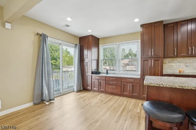 a large kitchen with granite countertop wooden cabinets a dining table and chairs