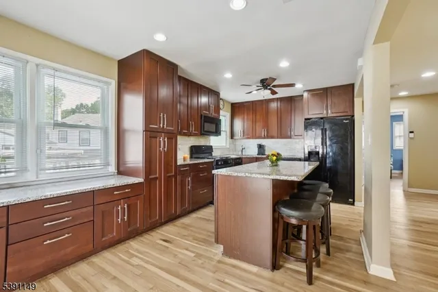a kitchen with kitchen island granite countertop wooden floors stainless steel appliances a sink and a refrigerator