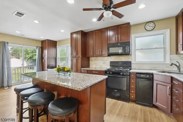 a kitchen with stainless steel appliances granite countertop a stove top oven a sink a dining table and chairs with wooden floor