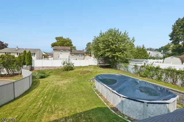 a swimming pool with outdoor seating and house in the background
