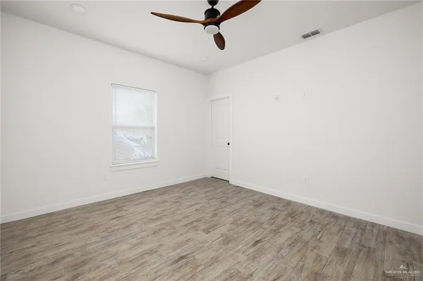 an empty room with wooden floor and windows