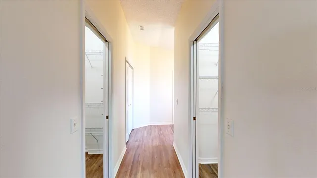 a view of a hallway with wooden floor and a bathroom