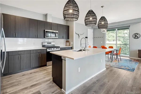 a kitchen with stainless steel appliances a sink a stove top oven a clock and cabinets