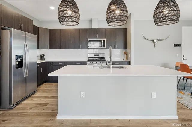 a view of kitchen with stainless steel appliances granite countertop a sink and refrigerator