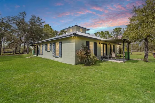 a view of a house with backyard and trees