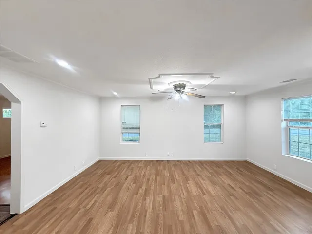a view of empty room with wooden floor and fan