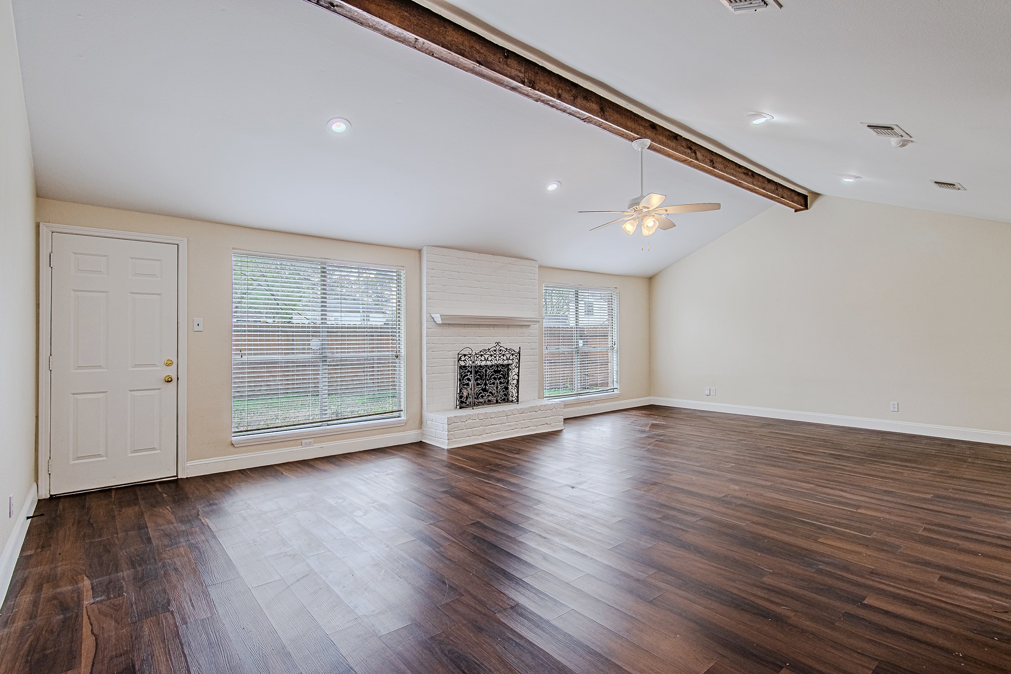 17811 Hawk Haven Lane Spring, TX 77379 - Photo 11 of 24 Spacious living room with rich flooring, a painted brick fireplace, abundant natural light, and direct access to the backyard. Ceiling fan has been updated since this photo was taken.