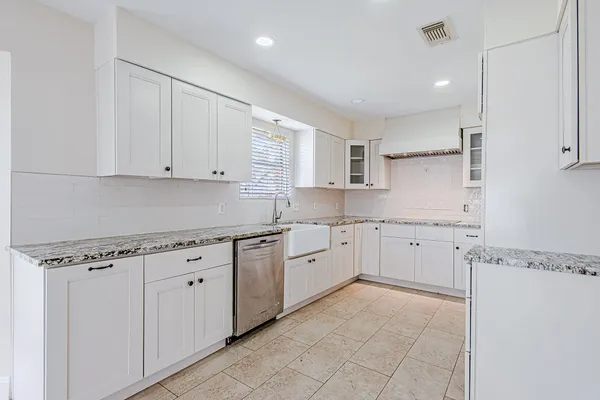 a kitchen with granite countertop white cabinets white stainless steel appliances with a sink and dishwasher