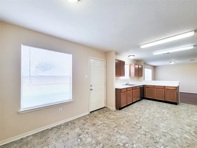 a view of an empty room with wooden floor and fan