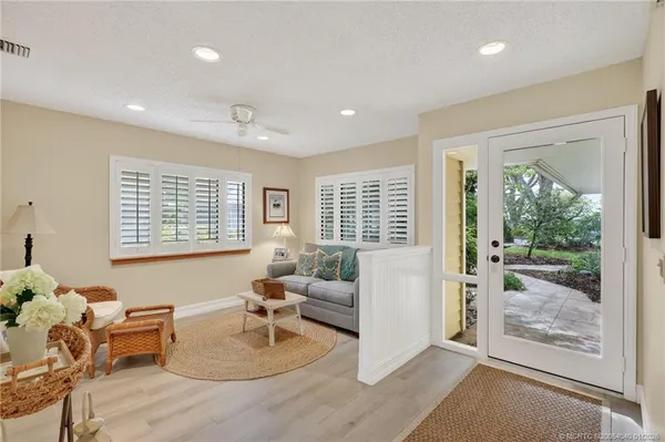 a living room with furniture large window and wooden floor