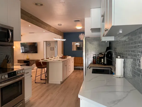 a kitchen with stainless steel appliances kitchen island granite countertop a stove top oven a sink dishwasher a dining table and chairs with wooden floor