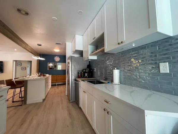 a kitchen with stainless steel appliances a sink dishwasher a stove top oven a refrigerator with island and chairs