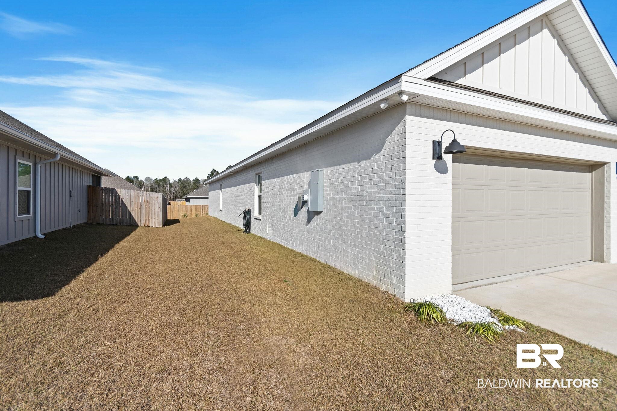 12919 Torrent Road Fairhope, AL 36532 - Photo 11 of 74 View of side of property with brick siding, board and batten siding, an attached garage, and concrete driveway