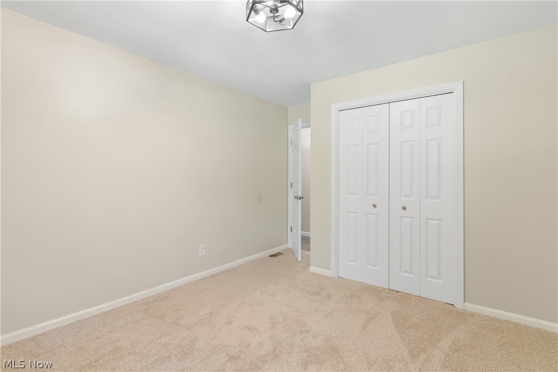 1075 Northeast River Road Lake Milton, OH 44429 - Photo 22 of 34 Neutral-toned room featuring light beige carpeting, white baseboards, and a contemporary ceiling light fixture