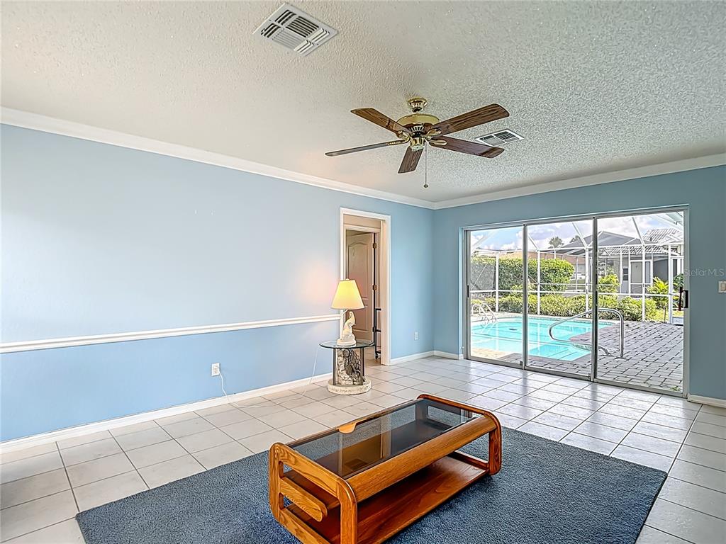 1039 Greenturf Road Spring Hill, FL 34608 - Photo 28 of 52 a living room with furniture pool table and a floor to ceiling window