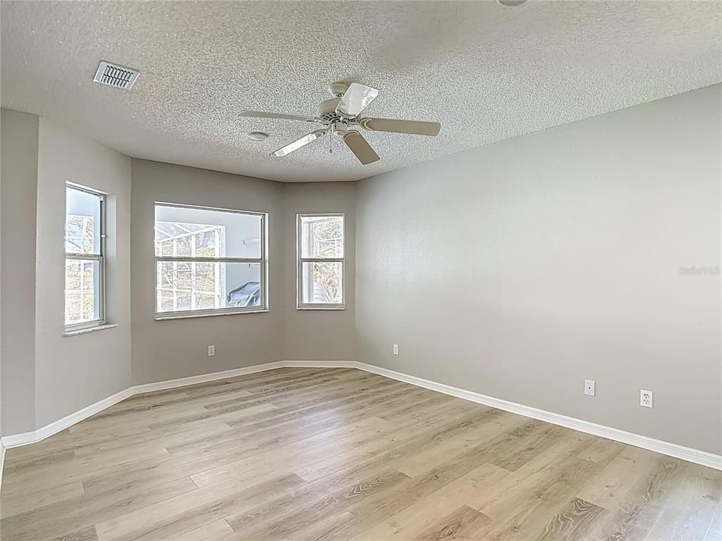 1039 Greenturf Road Spring Hill, FL 34608 - Photo 28 of 60 an empty room with wooden floor fan and windows