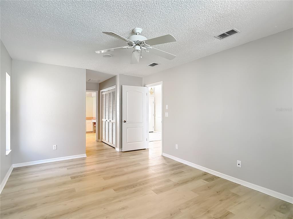 1039 Greenturf Road Spring Hill, FL 34608 - Photo 29 of 60 a view of an empty room with wooden floor and a ceiling fan
