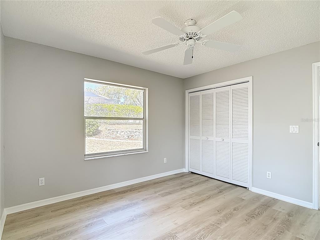 1039 Greenturf Road Spring Hill, FL 34608 - Photo 40 of 60 an empty room with wooden floor chandelier fan and windows