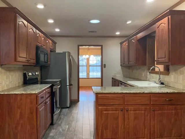 a kitchen with stainless steel appliances granite countertop wooden cabinets a sink and a granite counter tops