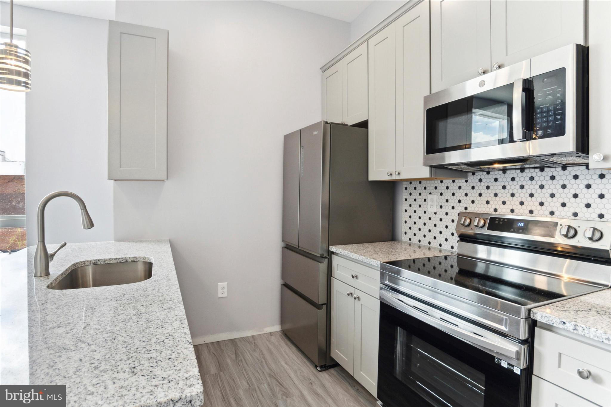 650 South Street, Unit 3 Philadelphia, PA 19147 - Photo 4 of 13 a kitchen with stainless steel appliances kitchen island a stove a sink and a microwave