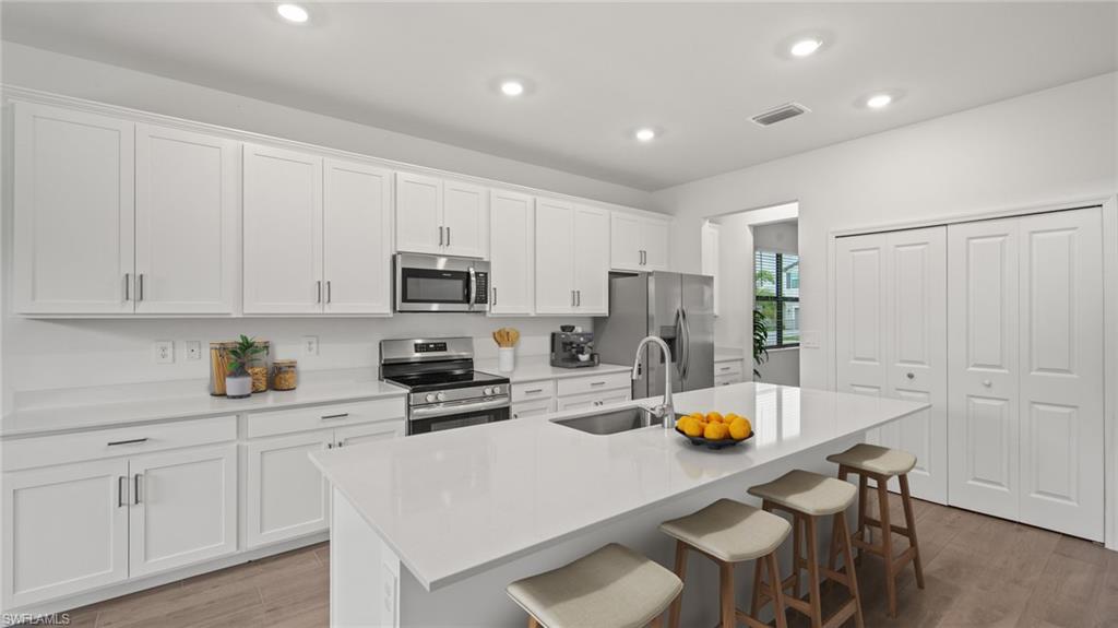 21090 Verawood Loop Estero, FL 33928 - Photo 4 of 17 a kitchen with stainless steel appliances a refrigerator a sink a stove cabinets and chairs