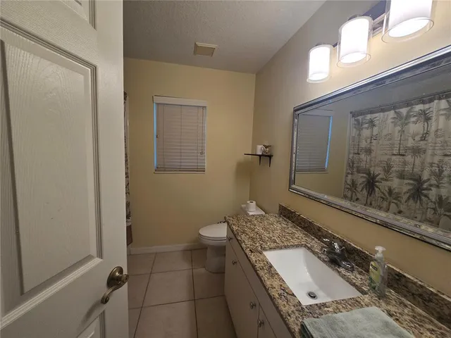 a bathroom with a granite countertop sink a toilet and shower