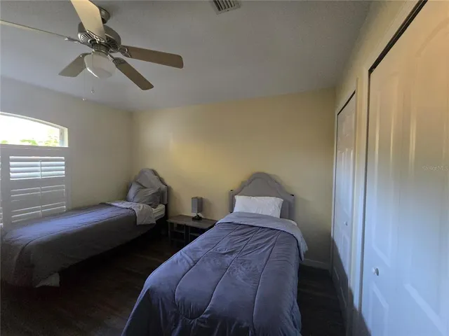 a bedroom with two beds and ceiling fan