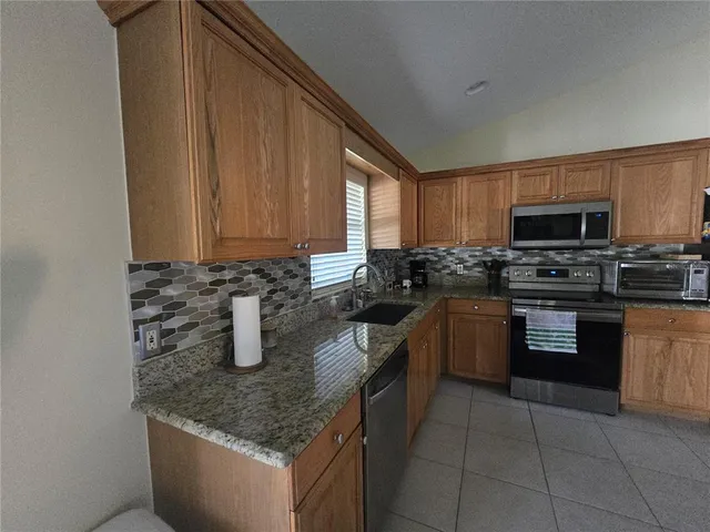 a kitchen with stainless steel appliances granite countertop a sink stove and microwave