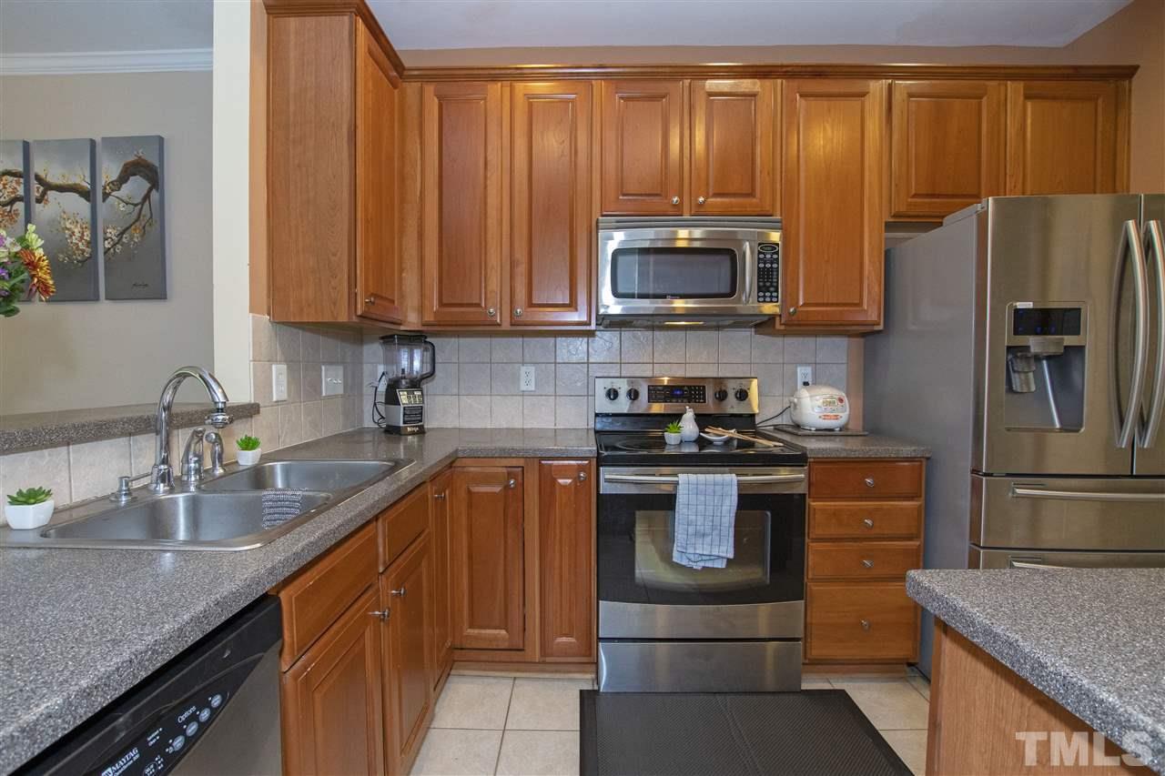 7879 Spungold Street Raleigh, NC 27617 - Photo 11 of 25 a kitchen with stainless steel appliances granite countertop a refrigerator stove and sink
