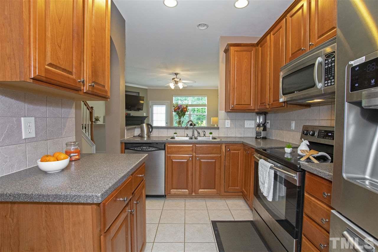 7879 Spungold Street Raleigh, NC 27617 - Photo 13 of 25 a kitchen with stainless steel appliances granite countertop a sink a stove a microwave and cabinets
