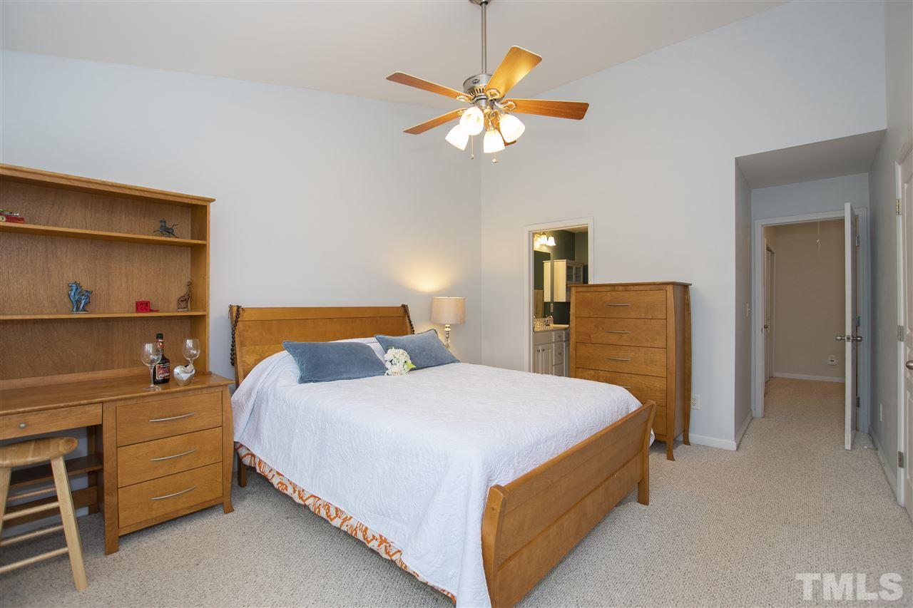7879 Spungold Street Raleigh, NC 27617 - Photo 17 of 25 a bedroom with a bed and a chandelier