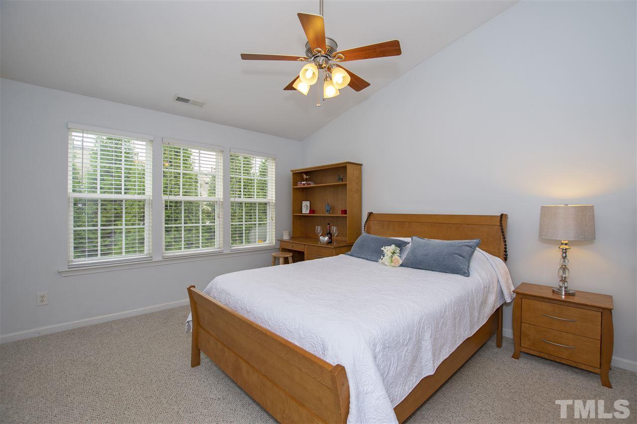 7879 Spungold Street Raleigh, NC 27617 - Photo 18 of 25 a bedroom with a bed and a chandelier