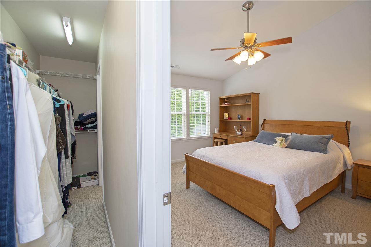 7879 Spungold Street Raleigh, NC 27617 - Photo 19 of 25 a bedroom with a large bed and a chandelier