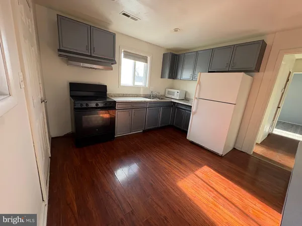 a kitchen with wooden floors and white appliances