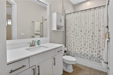 a bathroom with a sink a toilet a mirror and shower curtain