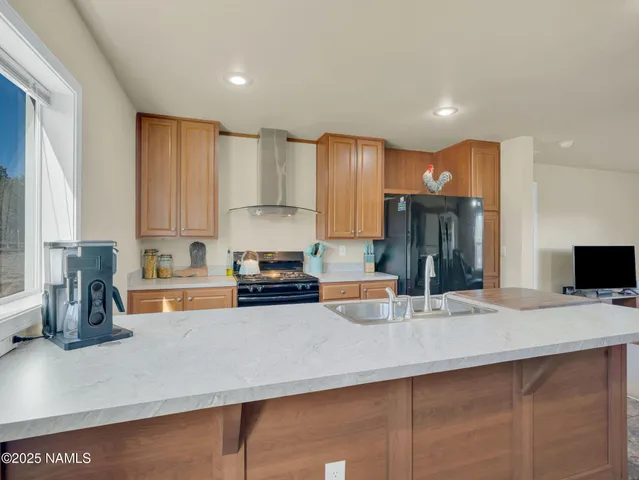 a kitchen with stainless steel appliances a sink a stove a microwave a refrigerator and cabinets