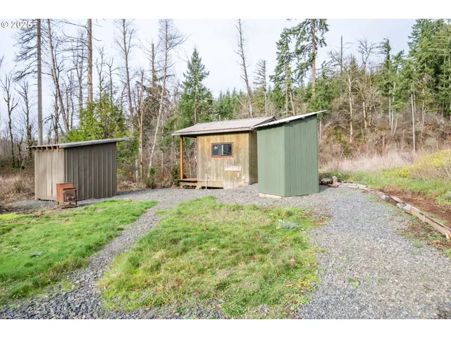 a backyard of a house with plants and trees with wooden fence