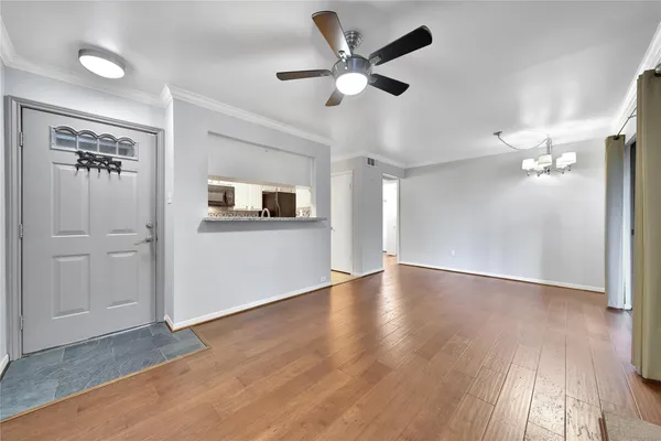 a view of a livingroom with a ceiling fan wooden floor and a ceiling fan