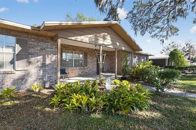 a view of yellow house with large windows and flower plants