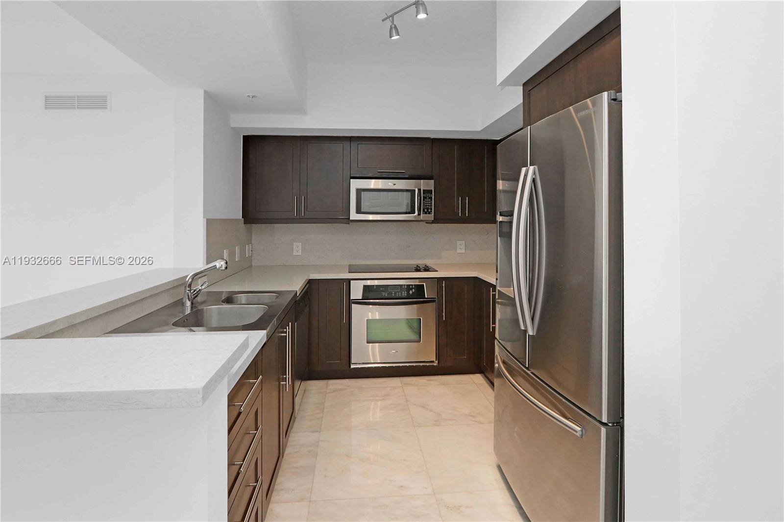 888 Douglas Road, Unit 1203 Coral Gables, FL 33134 - Photo 12 of 27 a kitchen with stainless steel appliances granite countertop a refrigerator and a stove