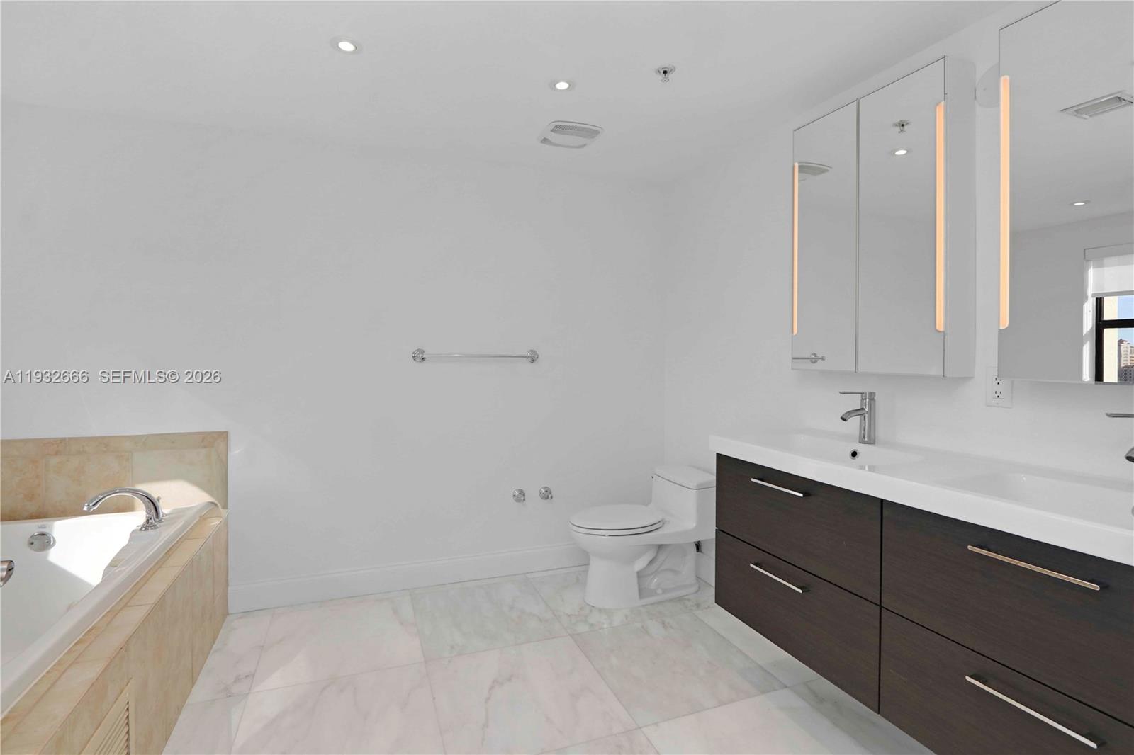 888 Douglas Road, Unit 1203 Coral Gables, FL 33134 - Photo 21 of 27 a bathroom with a toilet sink vanity and mirror